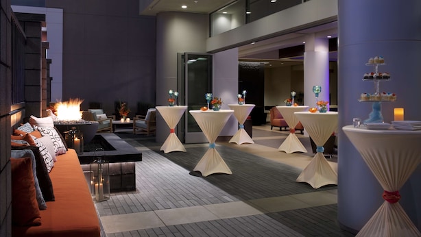 A modern indoor patio area with a fire feature, multiple tables with white tablecloths, and a dessert display. - HYATT house San Jose/Silicon Valley (San Jose)