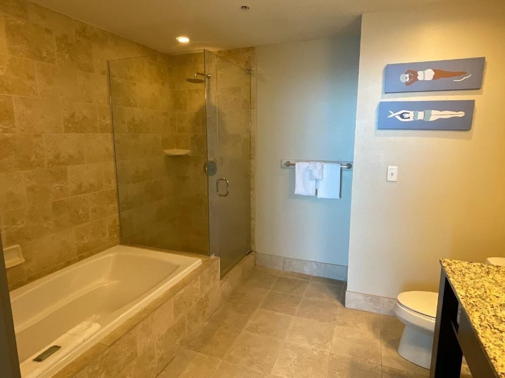 Une salle de bain avec une douche à parois de verre, une baignoire et des toilettes.