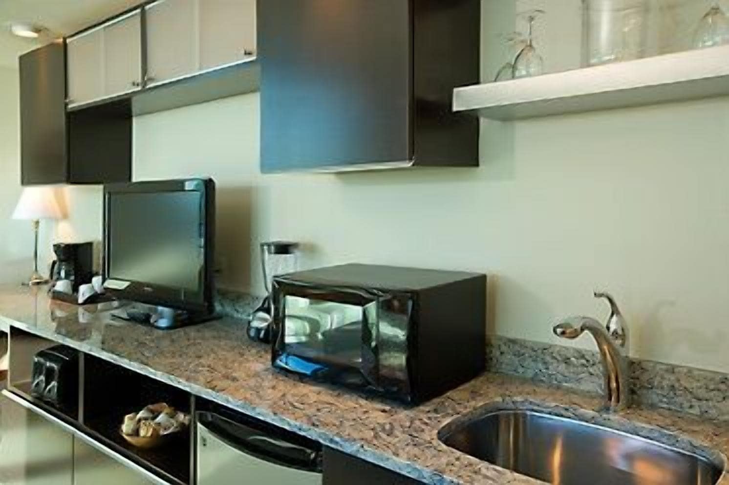 A modern kitchen with a built-in microwave, a coffee maker, and a sink.