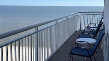 Un balcon avec vue sur la mer, doté d’une balustrade et de plusieurs chaises.