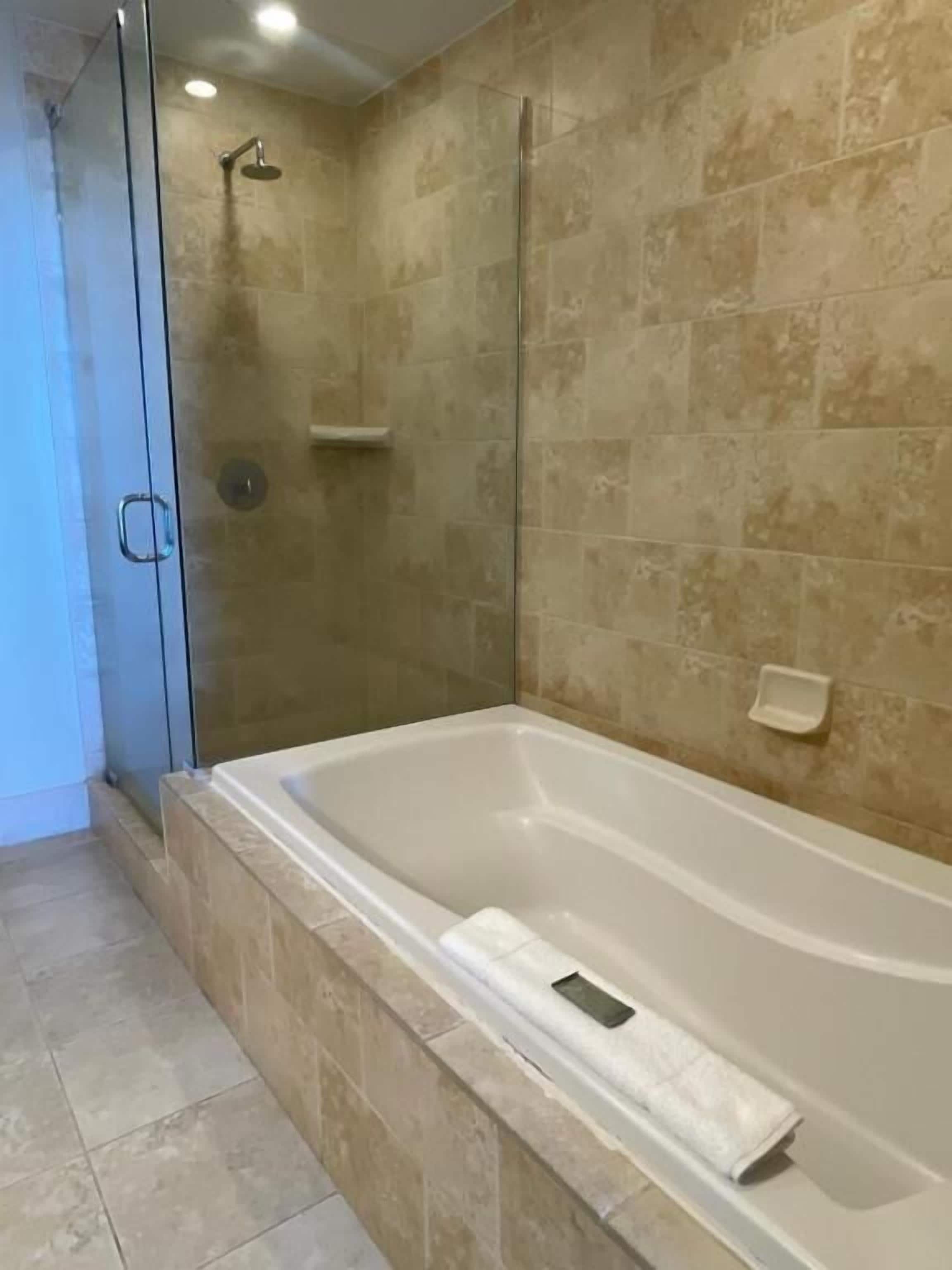 Un baño con bañera, ducha y puerta de cristal.