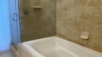 Un baño con bañera, ducha y puerta de cristal.