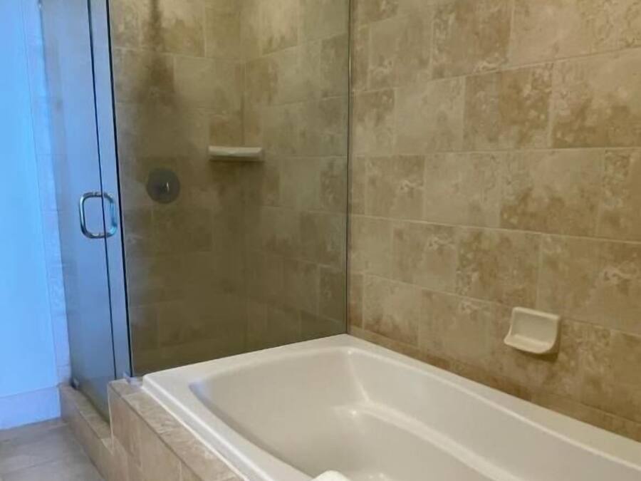Un baño con bañera, ducha y puerta de cristal.