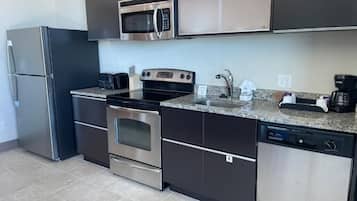 A modern kitchen with stainless steel appliances, a granite countertop, and dark cabinetry.