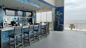 Zona de bar con vistas al océano, que incluye una barra con taburetes y un revestimiento azul de azulejos.