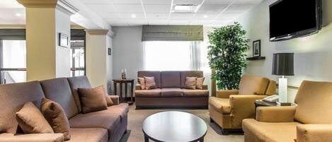 Una sala de estar moderna con un conjunto de sofás, una mesa de centro y un televisor montado en la pared.