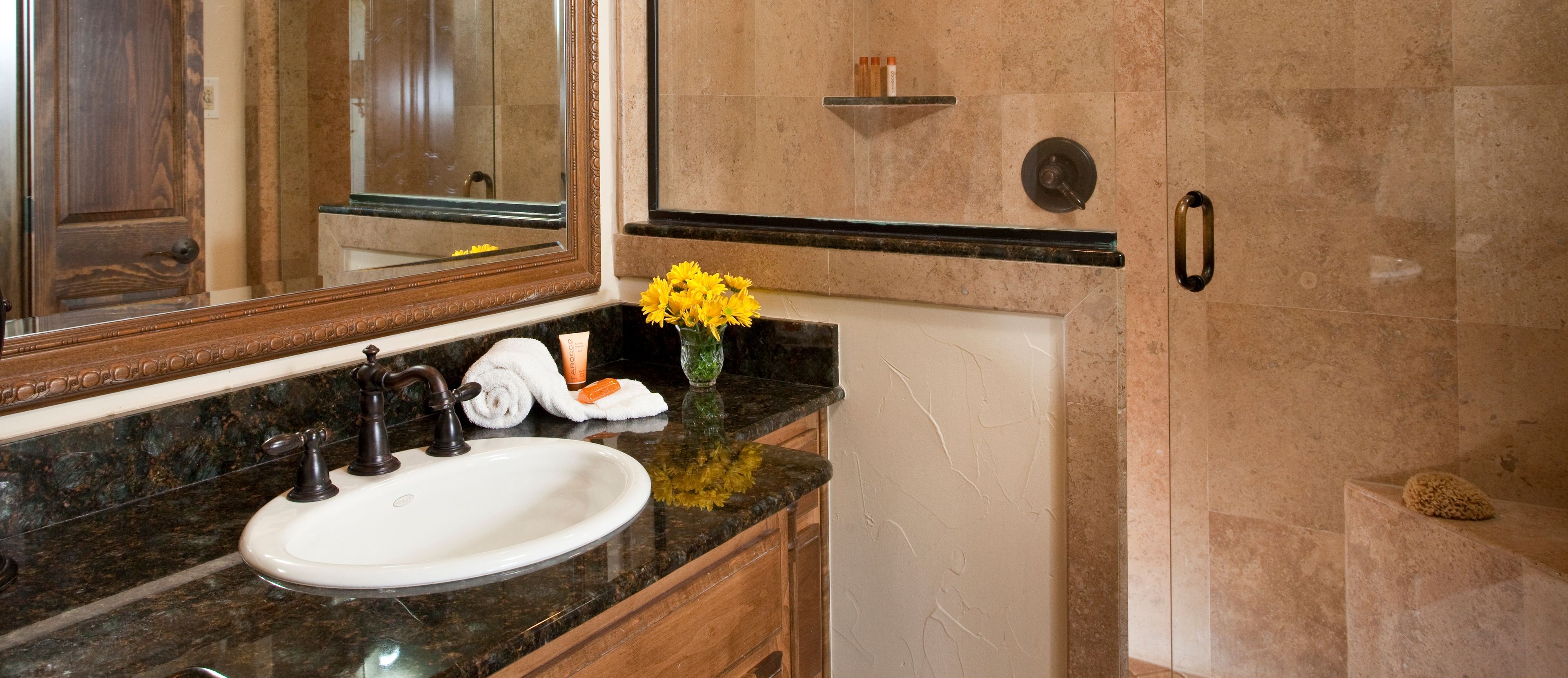 A bathroom with a white sink, dark granite countertop, a mirror, and a towel rack.