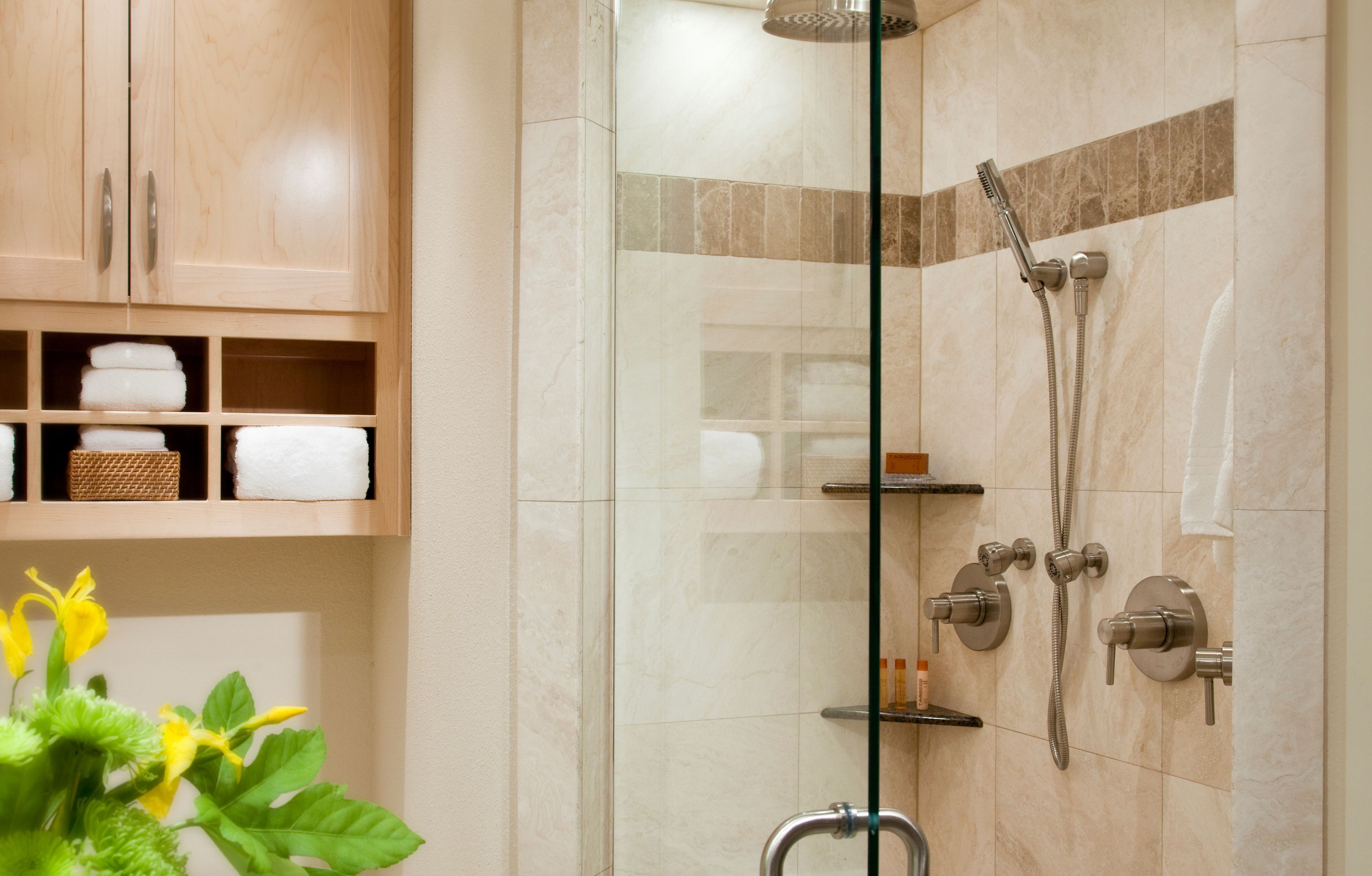 Un baño moderno con cabina de ducha de vidrio, armarios de madera y un estante con toallas.