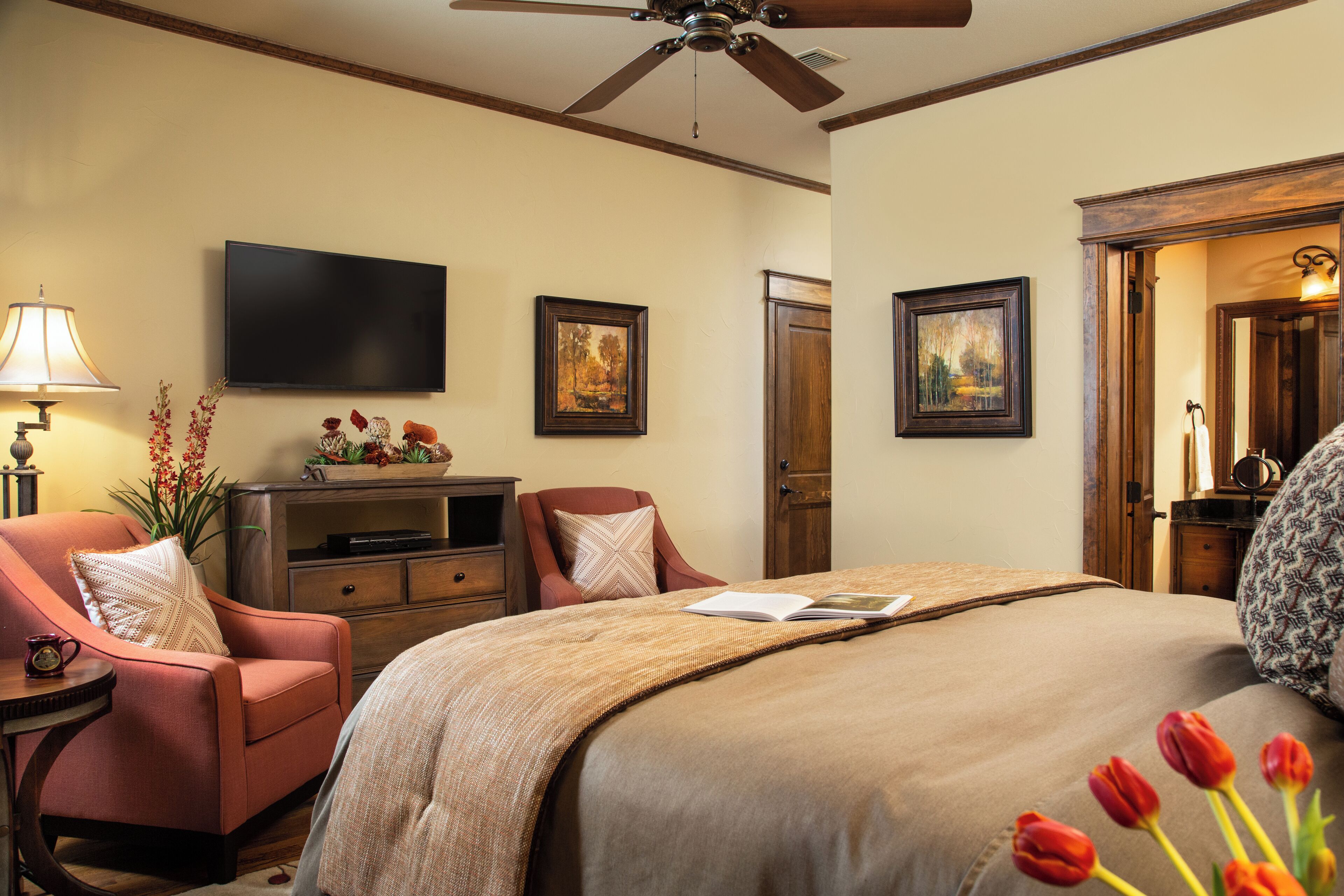 A bedroom with a bed, a television, a chair, a desk, and a door.