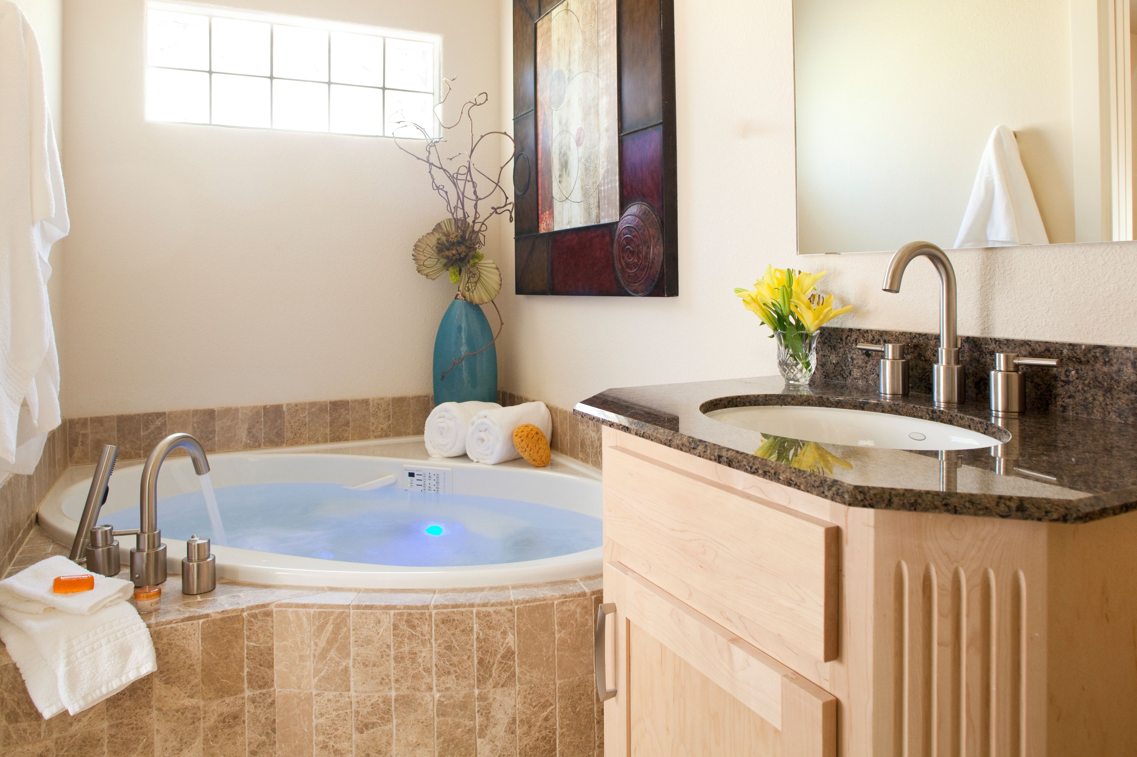A modern bathroom with a freestanding bathtub, a granite countertop, and a large mirror.