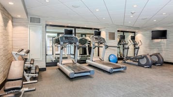 A gym with treadmills, elliptical machines, and weight benches.