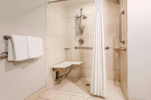 A walk-in shower with a grab bar, a white towel rack, and a small shelf. - Courtyard by Marriott Amarillo Downtown (Amarillo)