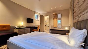 A modern bedroom with a large bed, a desk, a chair, and a TV.