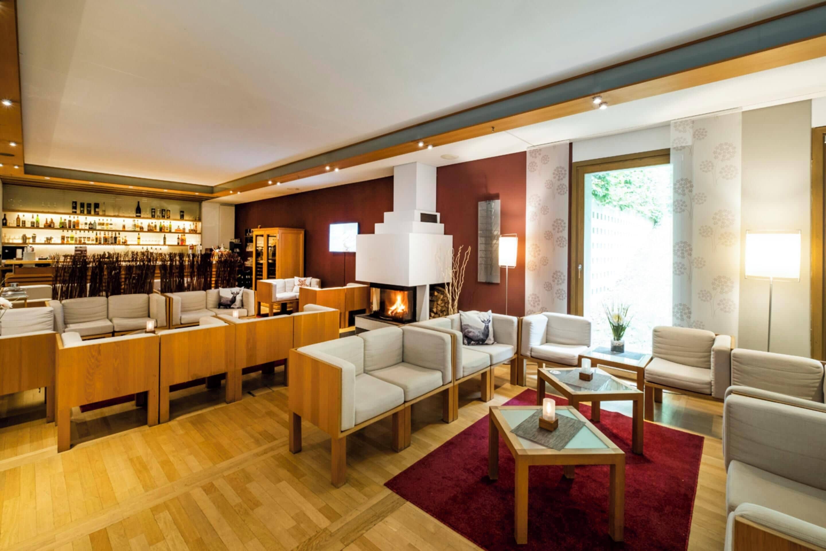 A modern hotel lobby with a bar area, seating arrangements, and a fireplace.