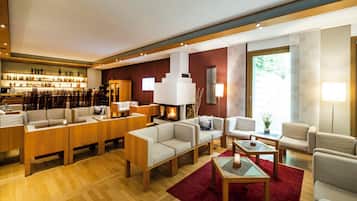 A modern hotel lobby with a bar area, seating arrangements, and a fireplace.