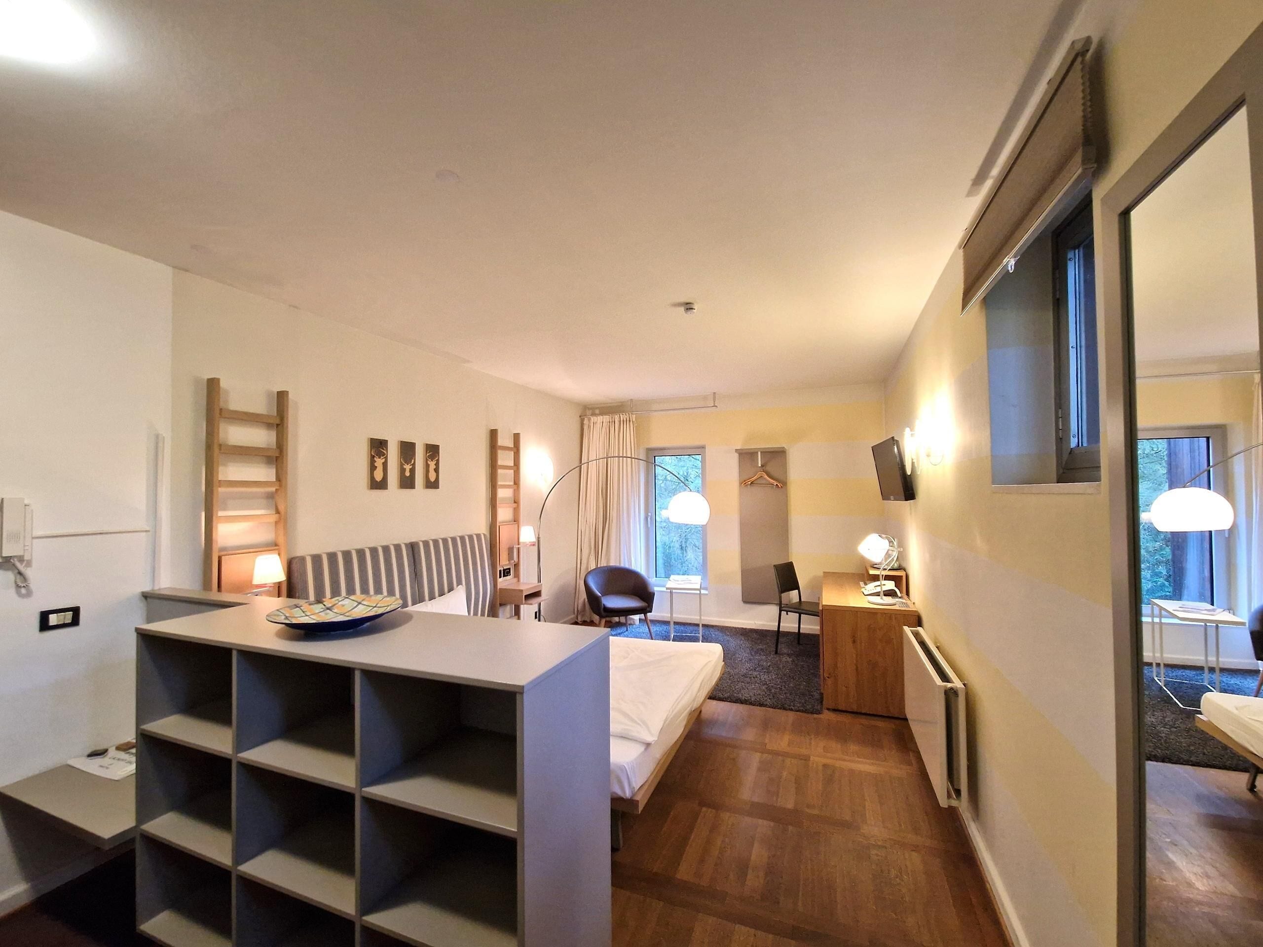 Una habitación de hotel con cama, escritorio, silla, armario y televisión.