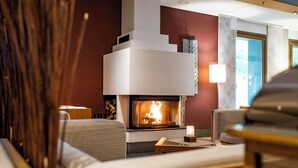A modern living room with a fireplace, comfortable seating, and a view of the outdoors. - Ringhotel Schorfheide I Waldresort Werbellinsee (Joachimsthal)