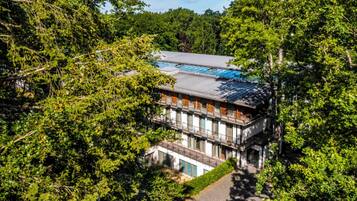 A multi-story building with a flat roof, surrounded by dense greenery.