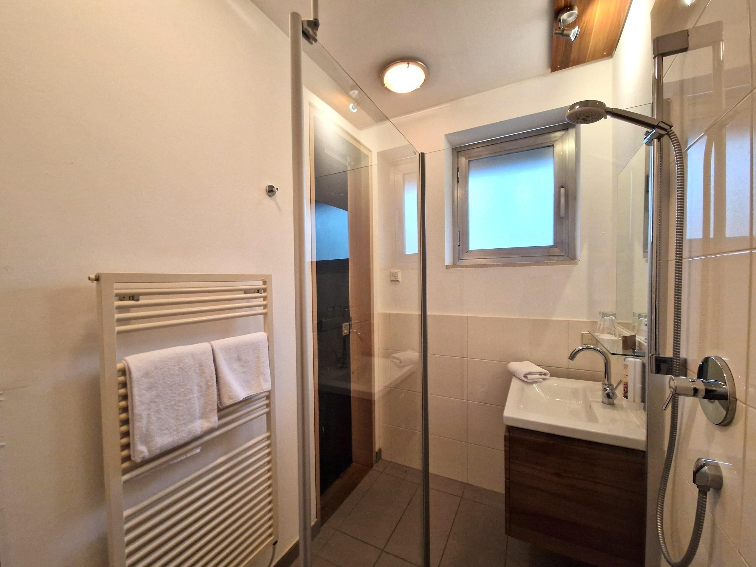 A modern bathroom with a glass shower enclosure, a built-in sink, and a towel rack.