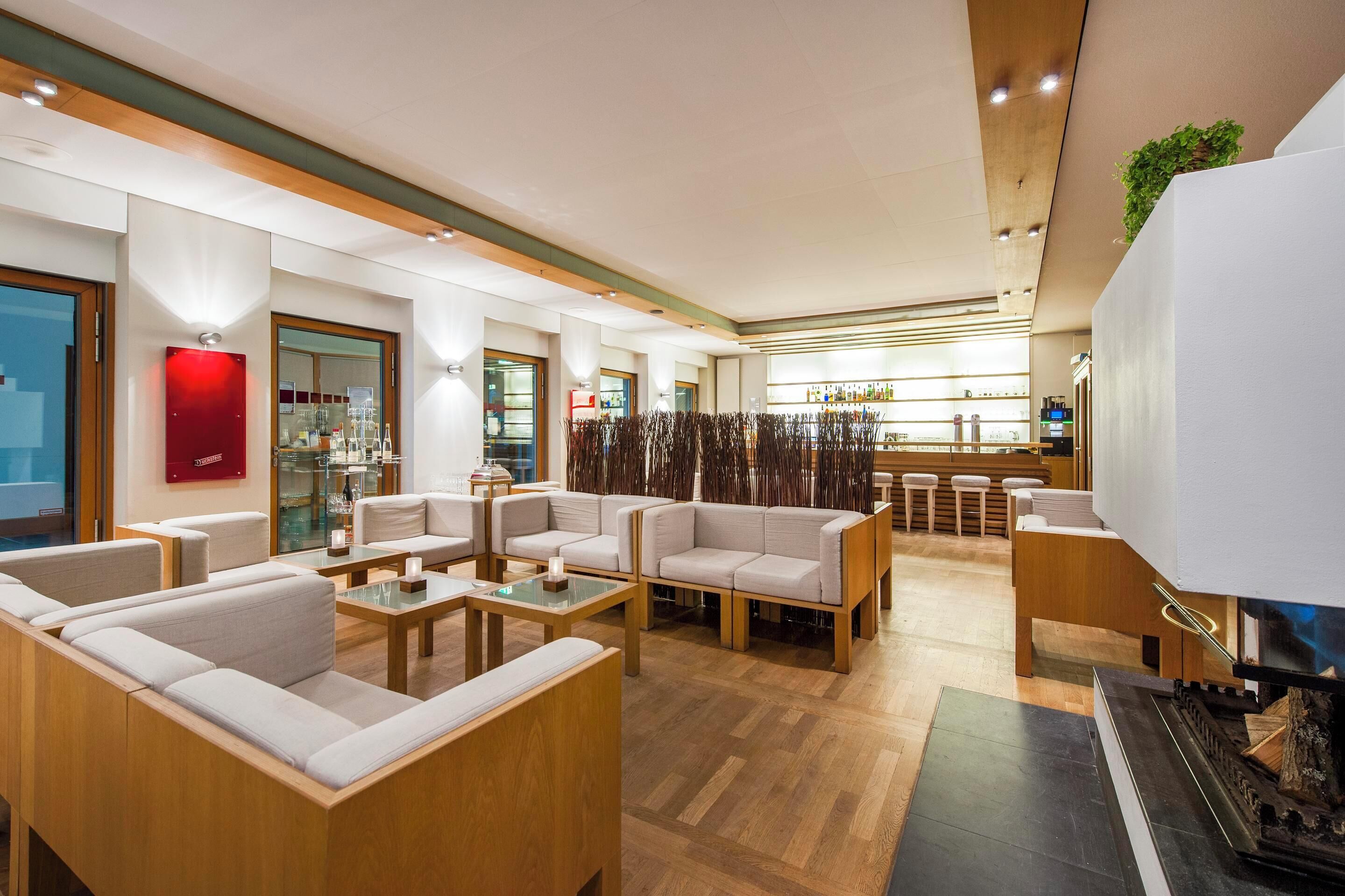 Un moderno vestíbulo de hotel con áreas de estar, un bar y una chimenea.