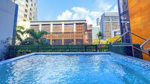 A swimming pool with a tiled edge, surrounded by buildings and greenery. - The B Hotel (Muntinlupa)
