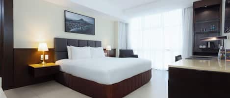 A modern hotel room with a large bed, bedside lamps, a desk with a coffee machine, and a view of a cityscape through the window.