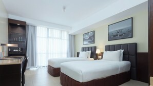 A hotel room with two beds, a desk, a coffee machine, and a view of the sea. - The B Hotel (Muntinlupa)