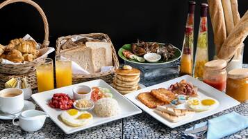 A breakfast spread with croissants, toast, eggs, and various condiments on a tiled table.
