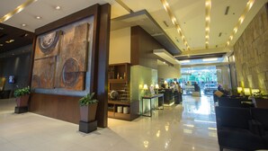 A modern lobby with a large abstract painting, a reception desk, and a seating area. - The B Hotel (Muntinlupa)