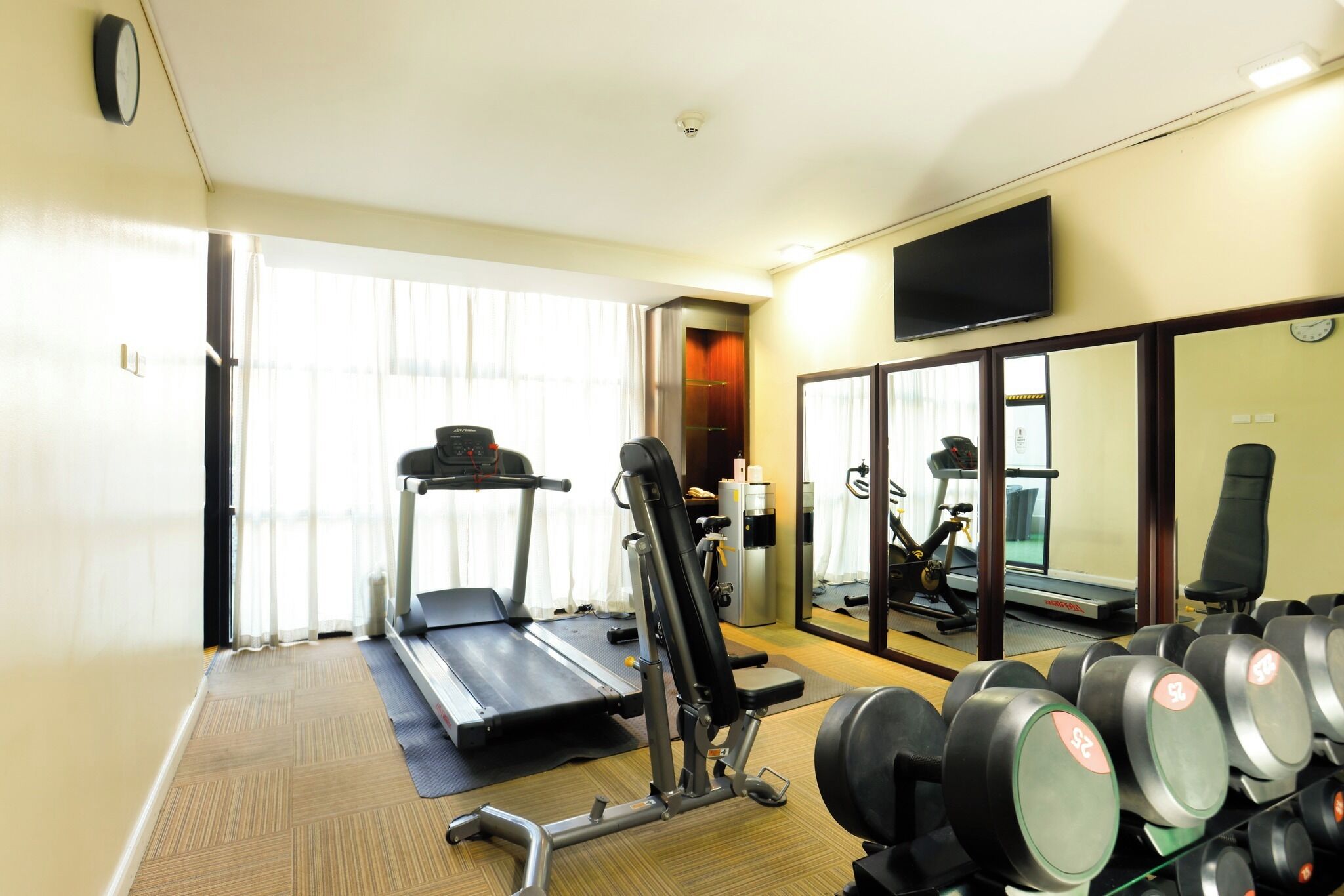 A gym with a treadmill, weight bench, and dumbbells.