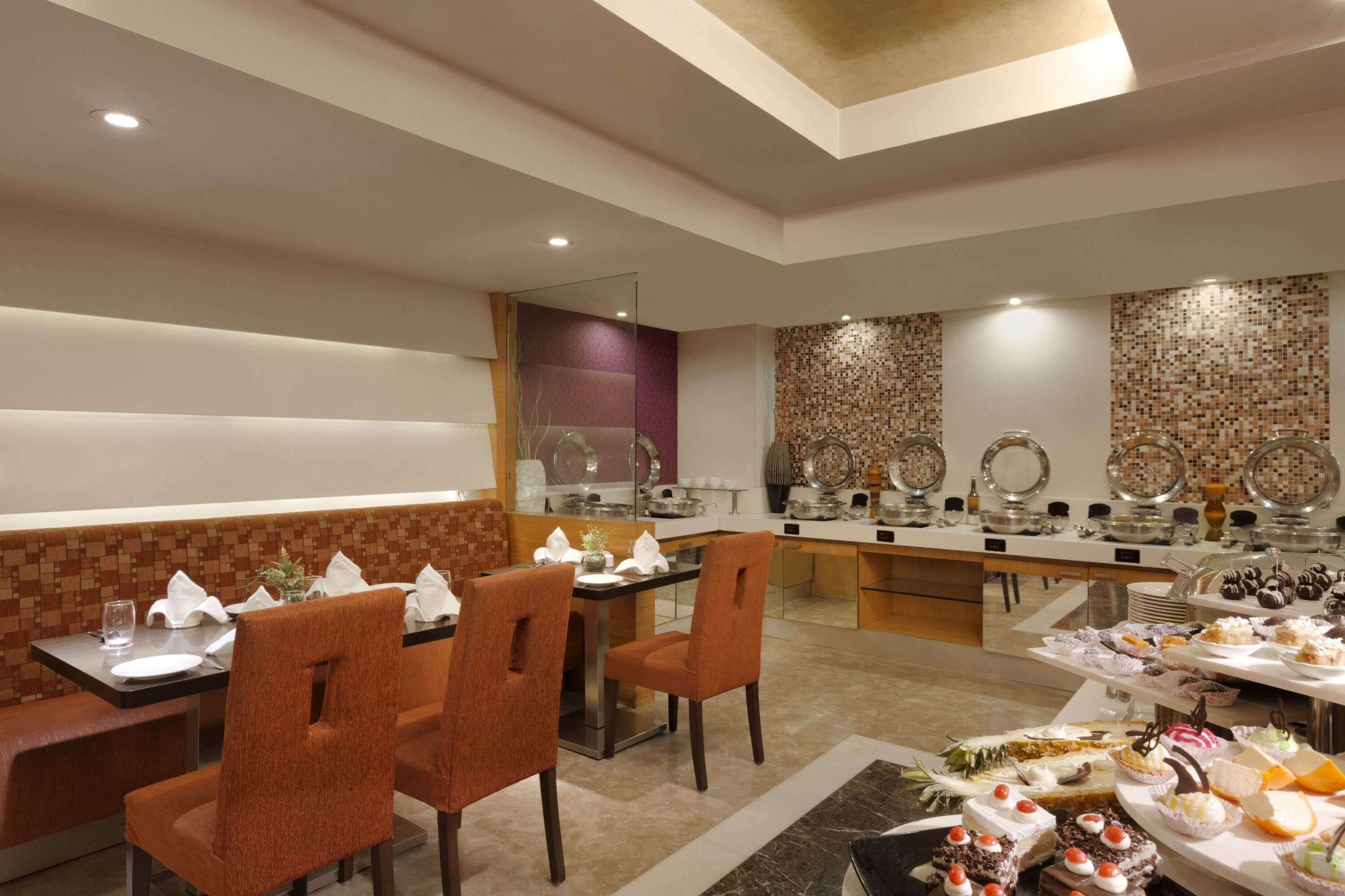 A restaurant with a buffet setup, seating arrangements, and a decorative wall.