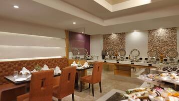 A restaurant with a buffet setup, seating arrangements, and a decorative wall.
