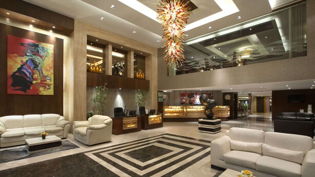 Eine großzügige Lobby mit hoher Decke, einem zentralen Kronleuchter und einer Rezeption.