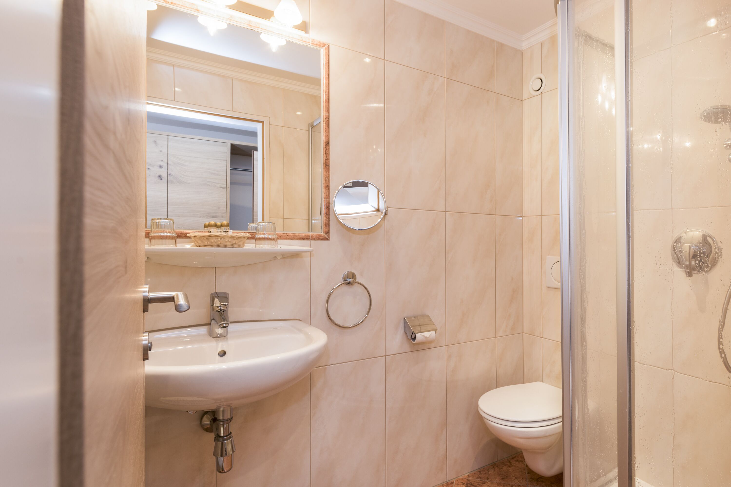 A modern bathroom with a sink, mirror, toilet, and shower.
