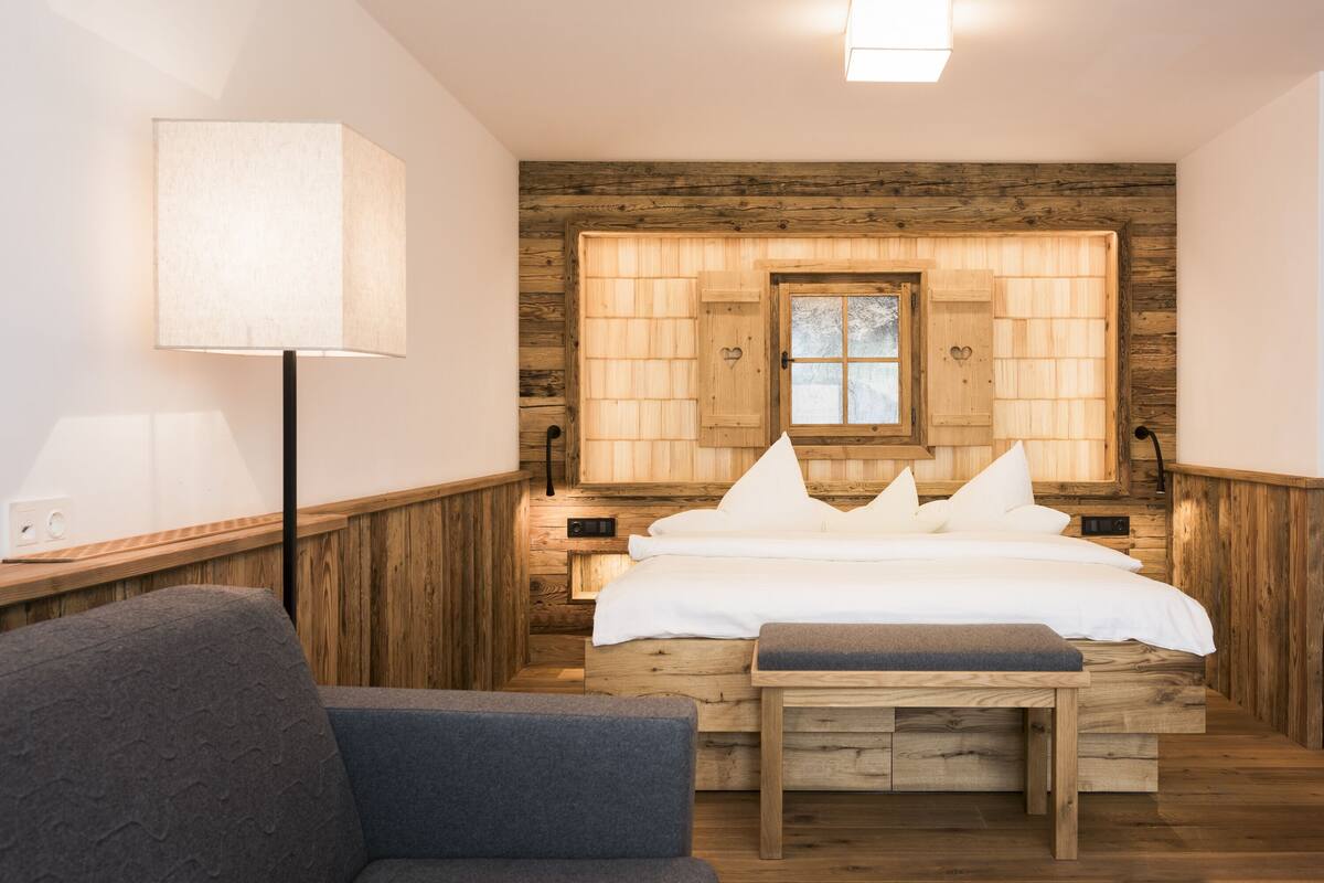 Une chambre confortable avec une tête de lit en bois, une table de chevet avec une lampe et un banc.
