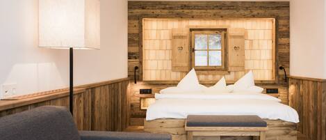 A cozy bedroom with a wooden headboard, a bedside table with a lamp, and a bench.