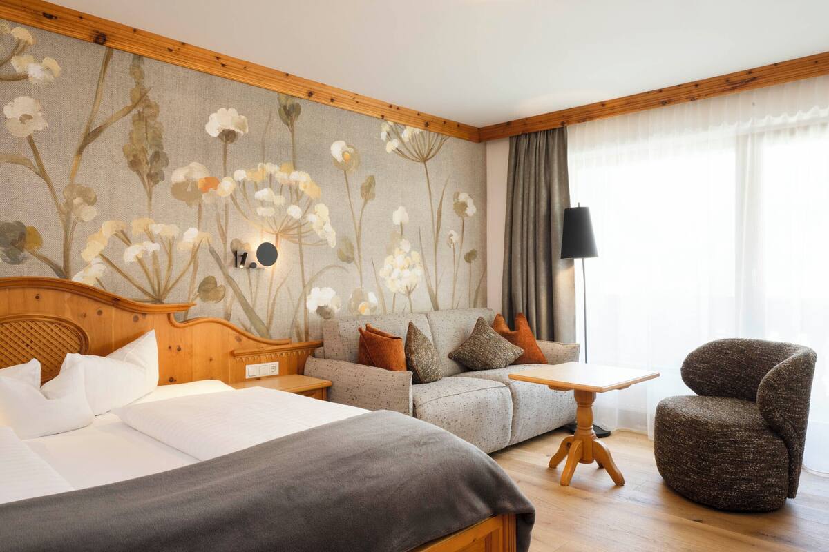 Une chambre d’hôtel avec un lit, un canapé, une petite table et une chaise.