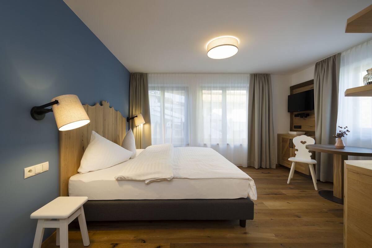 Une chambre d’hôtel moderne avec un grand lit, des lampes de chevet, une télévision, un bureau et une chaise.