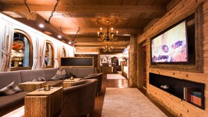 Ein gemütlicher Lounge-Bereich mit einer Couch, Sesseln und einem an der Wand befestigten Fernseher.