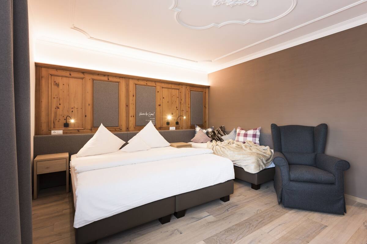 Une chambre à coucher avec un grand lit, une chaise, une table de chevet et une armoire en bois dotée de miroirs.