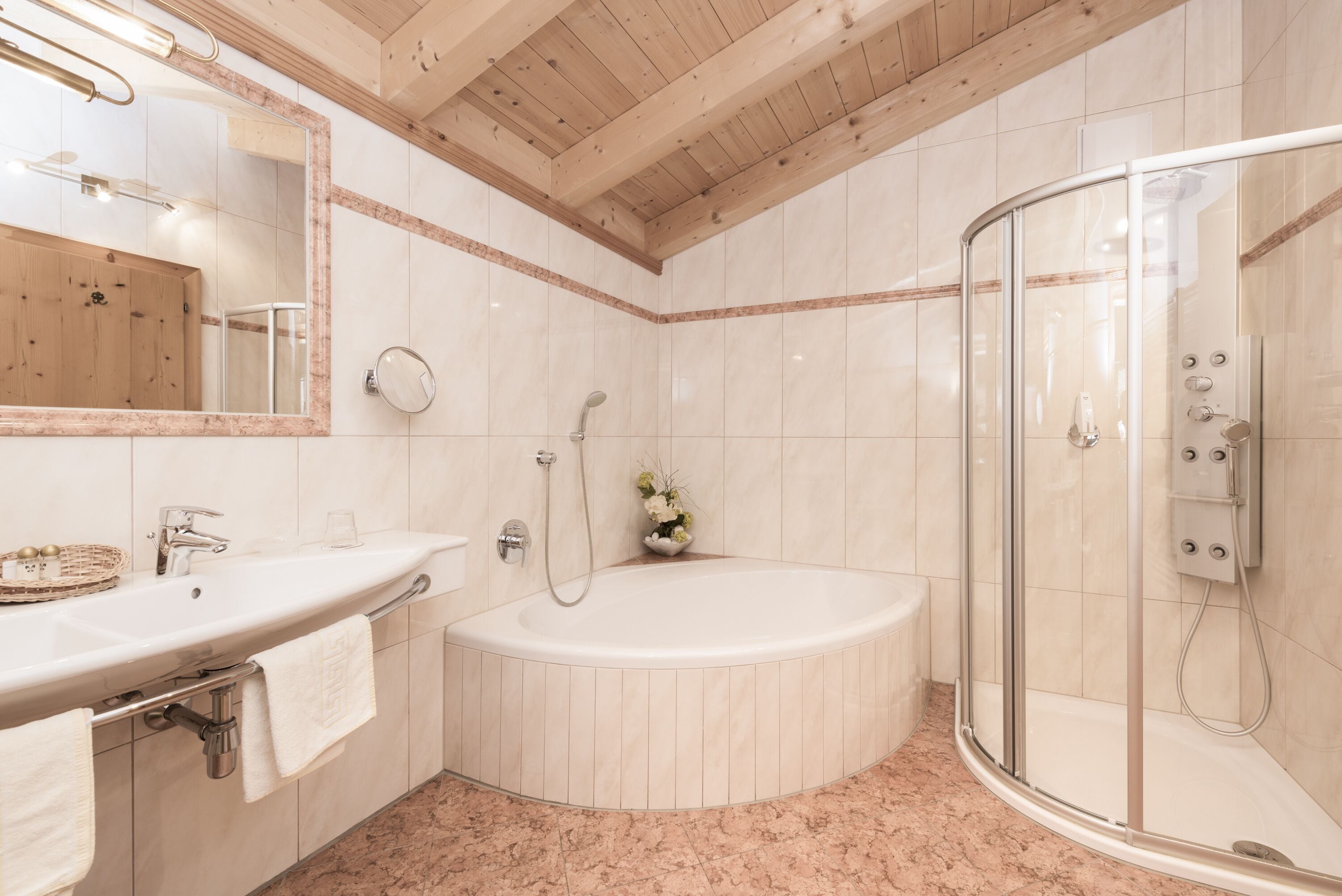 A modern bathroom with a large bathtub, a glass-enclosed shower, and a vanity with a mirror and sink.
