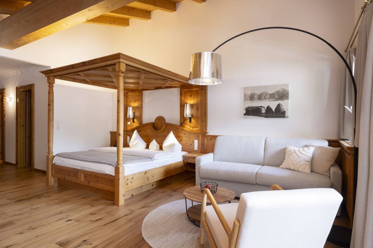 Une chambre à coucher avec un lit à baldaquin, un canapé, une petite table et une lampe.