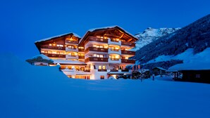 Ein mehrstöckiges Hotel mit Balkonen, verschneiter Umgebung und einer Bergkulisse.