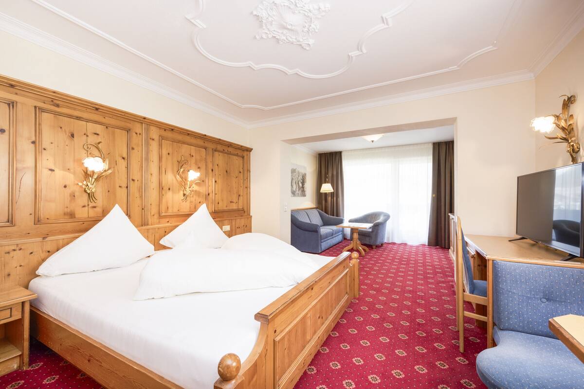 Une chambre d’hôtel avec un lit en bois, un bureau, une télévision et une chaise.