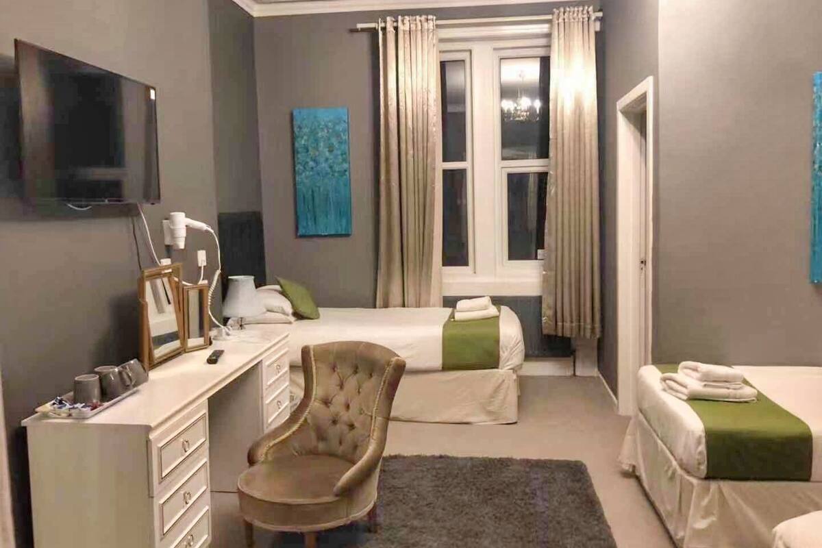 A hotel room with a bed, a chair, a desk, a television, and a window with curtains.