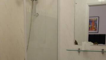 A bathroom with a glass-enclosed shower, a pedestal sink, and a small mirror above the sink.