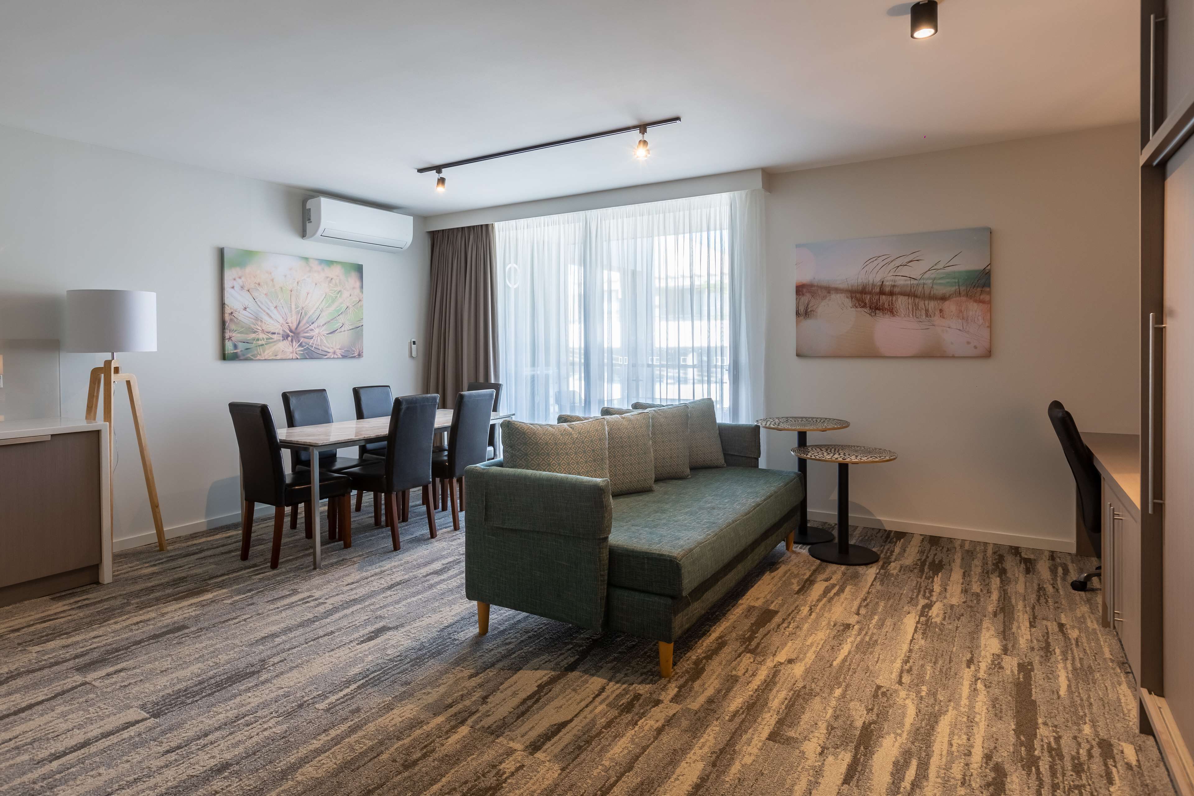 A modern living room with a sofa, dining table, chairs, and artwork on the walls.