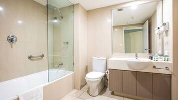 Un baño moderno con ducha envuelta en vidrio, inodoro blanco, bañera y tocador con lavamanos y espejo.