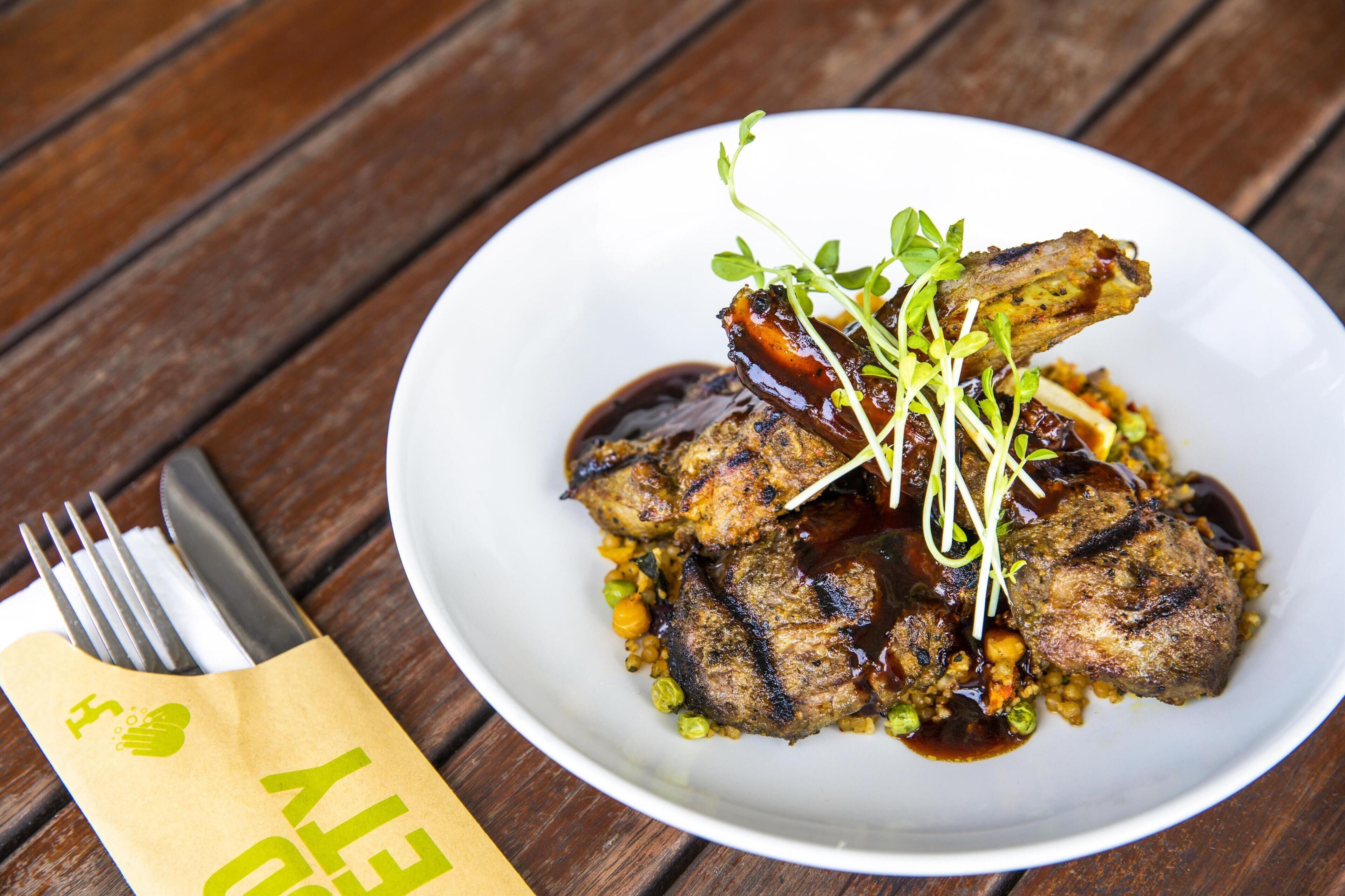 A plate of food with a fork and a napkin on a wooden table.