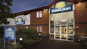 Edificio Days Inn con un letrero visible, entrada de cristal y fachada de ladrillo.